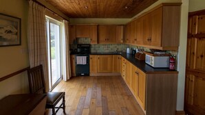 Eine Küche mit Holzausstattung, gefliestem Spritzschutz und einer Mikrowelle.