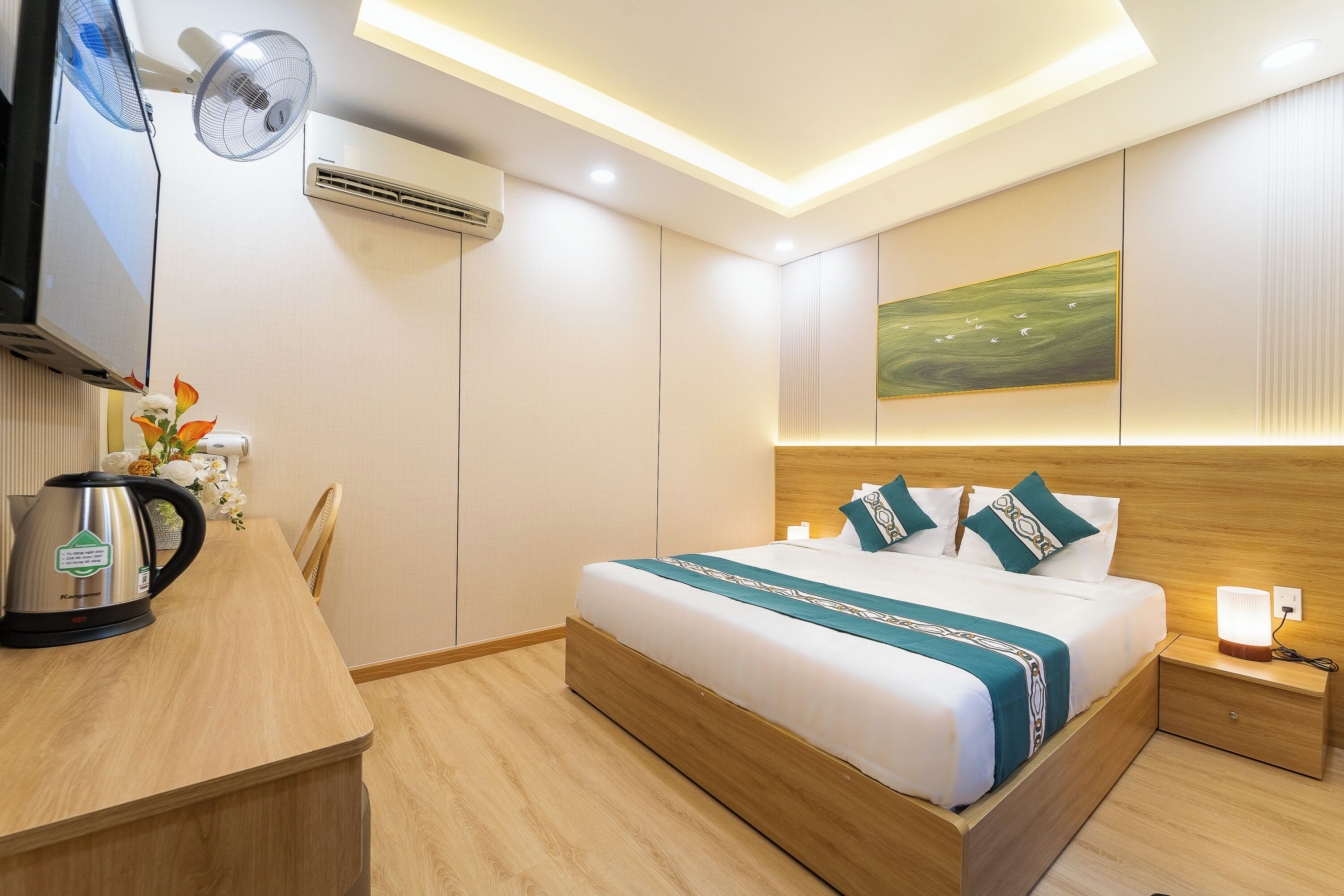 A hotel room with a bed, bedside table, lamp, and a wall-mounted TV.