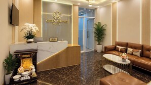 A hotel reception area with a marble counter, a sofa, a coffee table, and a reception desk. - Green Airport Hotel 2 (Ho Chi Minh City)
