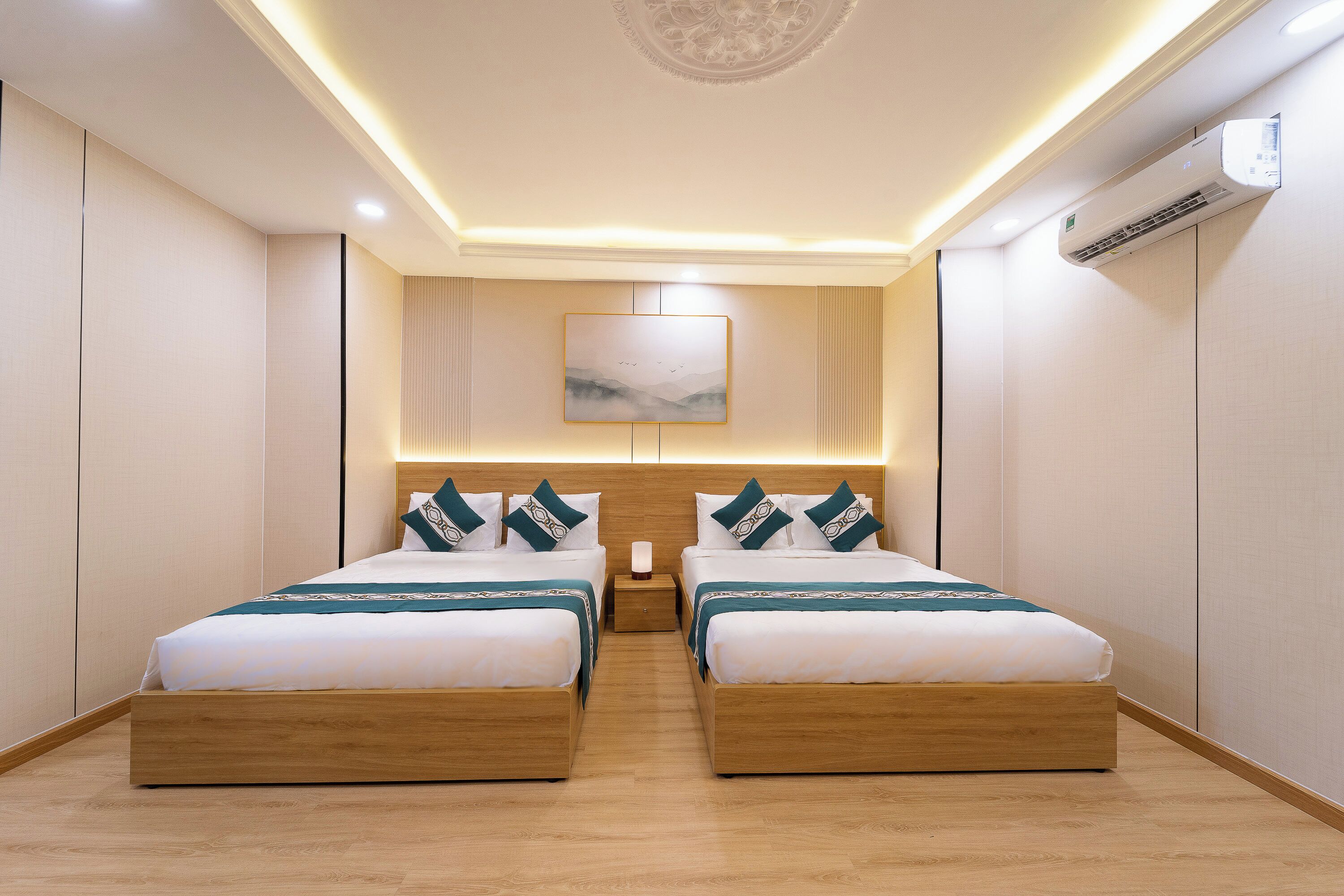 A hotel room with two beds, a wooden headboard, a painting on the wall, and an air conditioning unit.