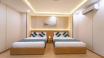 A hotel room with two beds, a wooden headboard, a painting on the wall, and an air conditioning unit.
