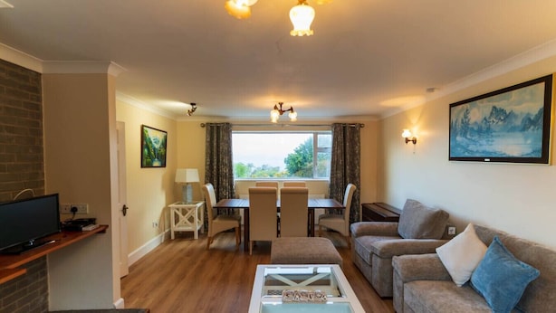 Una sala de estar con televisión, una mesa de comedor con sillas, un sofá y una mesa de centro.