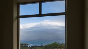 Una ventana con vistas a un paisaje costero, que incluye una masa de agua y tierra en la distancia.