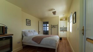 A bedroom with a bed, a bedside table, a wardrobe, and a window. - Finbarr’s House - Waterville (Waterville)