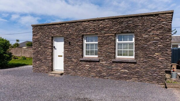 A small stone building with a white door and two windows. - Finbarr’s House - Waterville (Waterville)