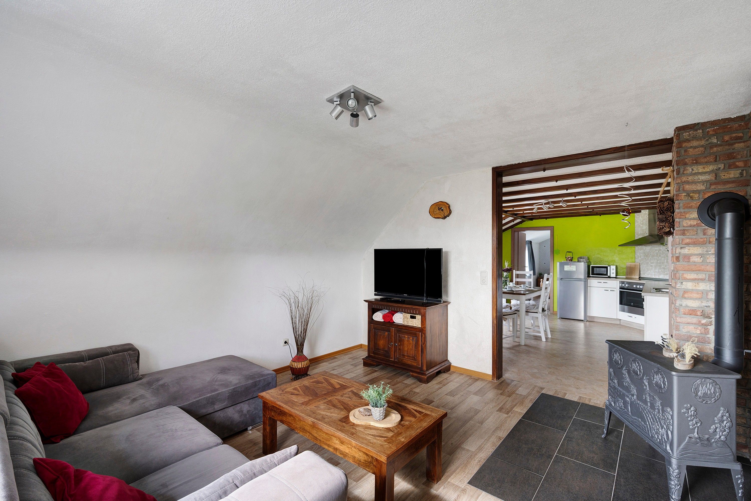 Een woonkamer met een bank, een salontafel, een televisie en een open haard.