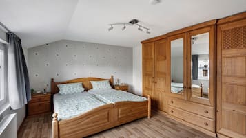 Ein Schlafzimmer mit einem hölzernen Bett, einem Nachttisch, einem Kleiderschrank und einer Deckenleuchte.