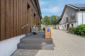 A building with a wooden exterior, a paved entrance, and a parking sign.