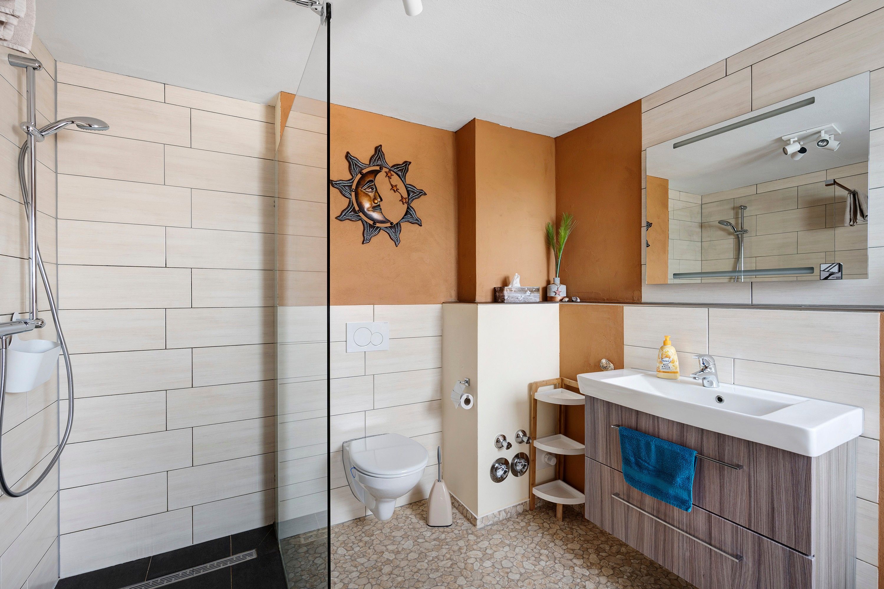 Une salle de bain moderne équipée d’une douche, de toilettes, d’un meuble-lavabo et d’un grand miroir.