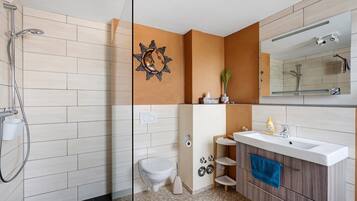 Une salle de bain moderne équipée d’une douche, de toilettes, d’un meuble-lavabo et d’un grand miroir.