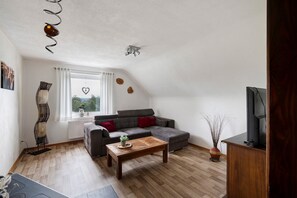 A modern living room with a grey sectional sofa, a wooden coffee table, and a television on a wooden stand.