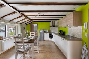 A kitchen with a dining area, a view to the outside, and a green wall. - Apartment 'Ferienwohnung Hohes Venn' with Wi-Fi (Monschau)