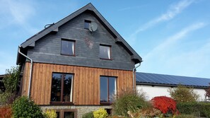 A two-story house with a sloped roof, wooden siding, and large windows. - Apartment 'Ferienwohnung Hohes Venn' with Wi-Fi (Monschau)