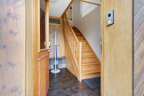 A wooden staircase leading to a landing with a coat rack and a door with a security device. - Apartment 'Ferienwohnung Hohes Venn' with Wi-Fi (Monschau)