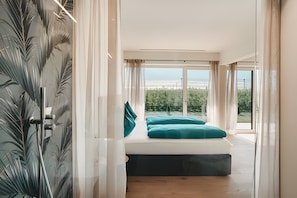 Ein Schlafzimmer mit Bett, Blick ins Freie und einer Dusche.