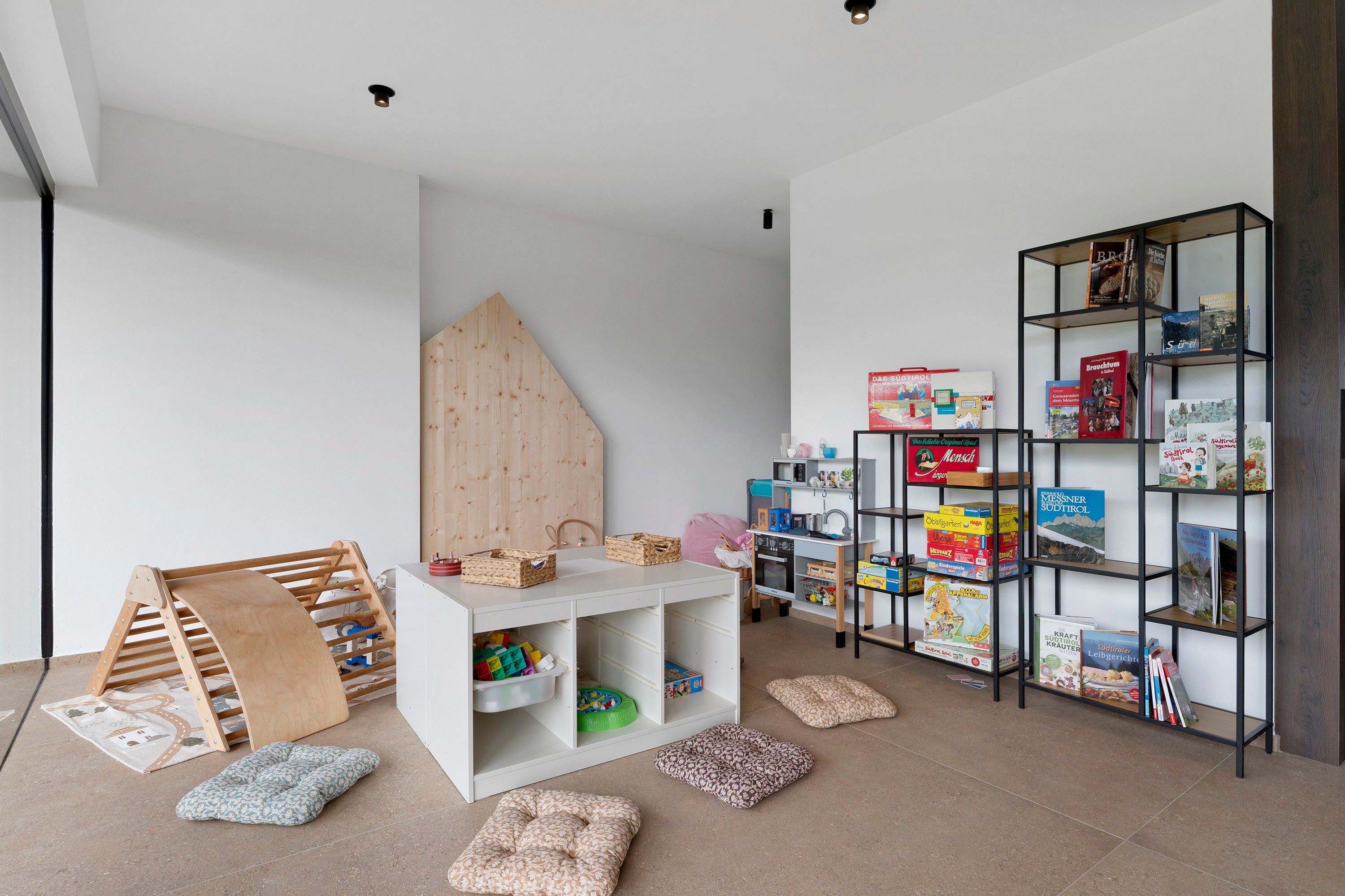 Een kinderspeelruimte met een witte tafel, opbergplanken en een houten klimstructuur.