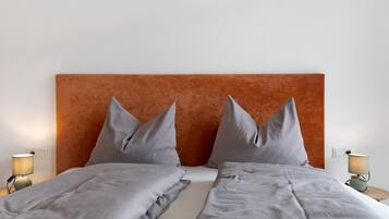 Un letto matrimoniale con testiera, due abat-jour e una parete in colori neutri.