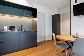 A modern kitchen with a built-in island, a dining area with a round table and chairs, and a flat-screen TV mounted on the wall. - Apartment 'Grafferhof III' with Mountain View, Wi-Fi and Air Conditioning (Bolzano)