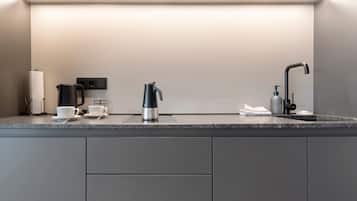 Une cuisine moderne équipée d’une machine à café intégrée, d’une bouilloire et d’un distributeur de savon.