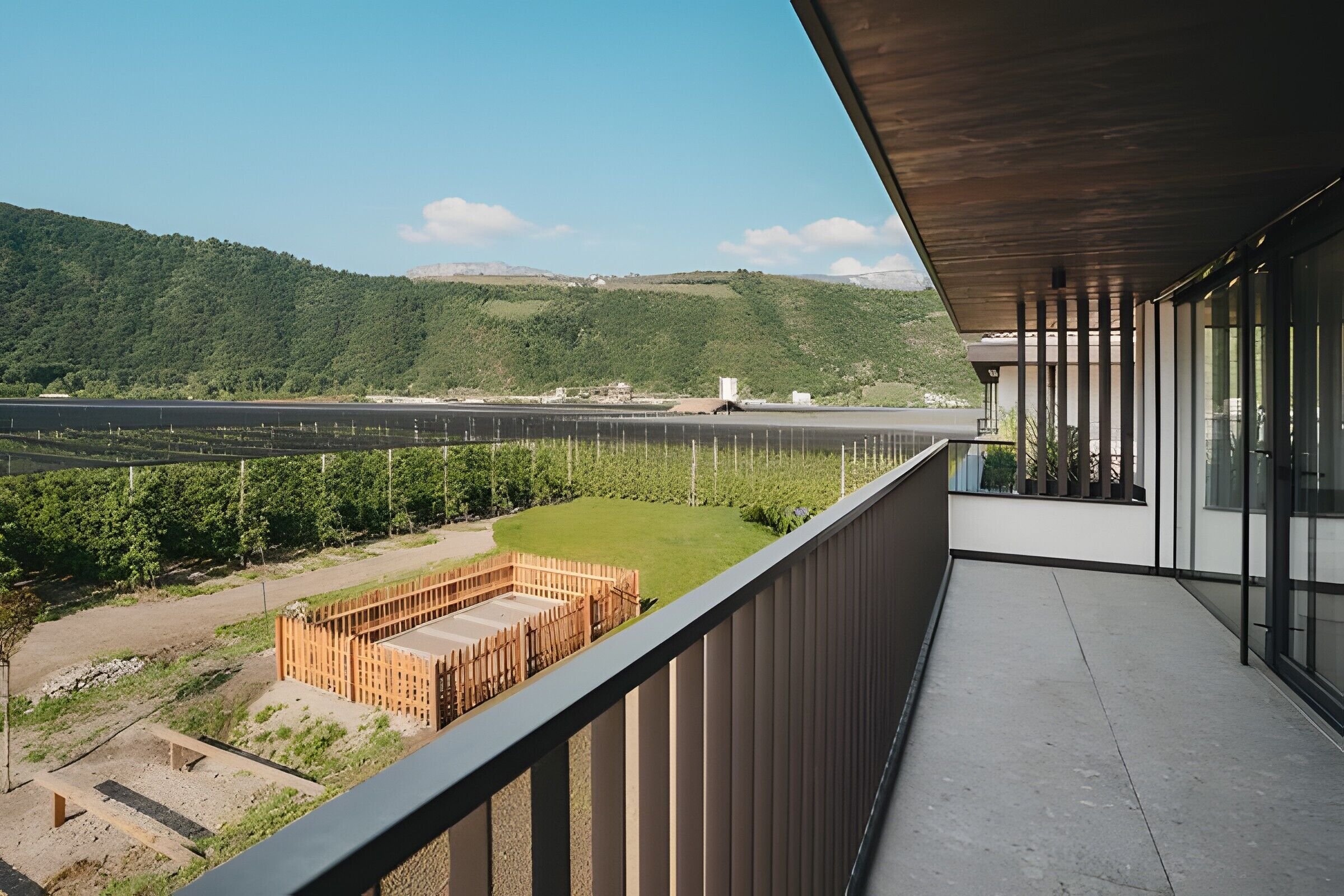 A balcony with a view of a green landscape and a distant runway.