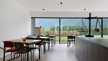 A modern interior with a dining area, a bar counter, and a view of a mountainous landscape.