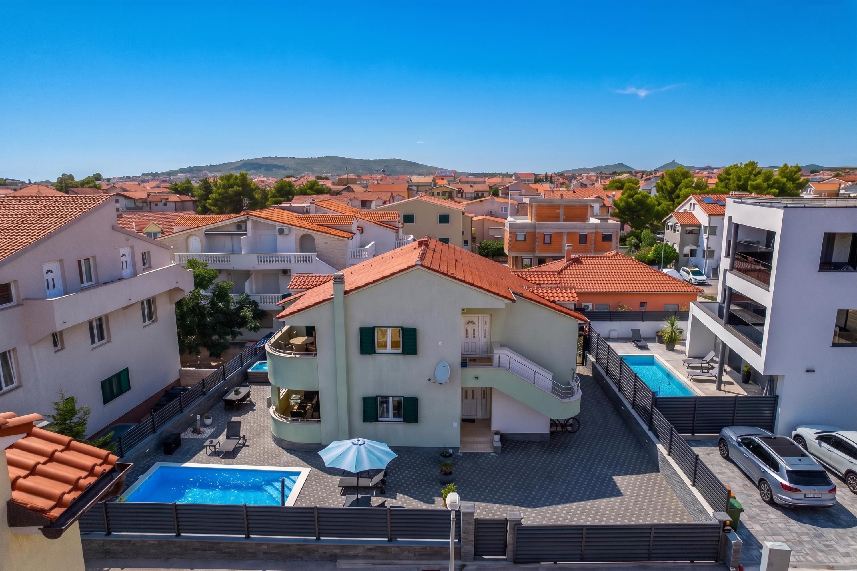 A residential building with a swimming pool, outdoor seating, and a view of the surrounding neighborhood.