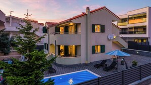 A two-story building with a swimming pool, outdoor seating, and a staircase leading to an upper level. - S Villa With Pool, Jacuzzi & Gym (Vodice)