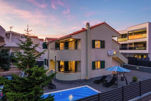 A two-story building with a swimming pool, outdoor seating, and a staircase leading to an upper level. - S Villa With Pool, Jacuzzi & Gym (Vodice)