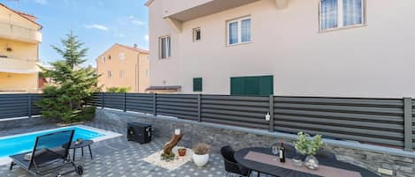 En bostadsbyggnad med en swimmingpool, utomhusmöbler och en mur av sten.