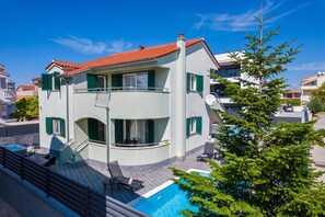 Ein zweistöckiges Gebäude mit Swimmingpool, Sitzgelegenheiten im Freien und einem Balkon.