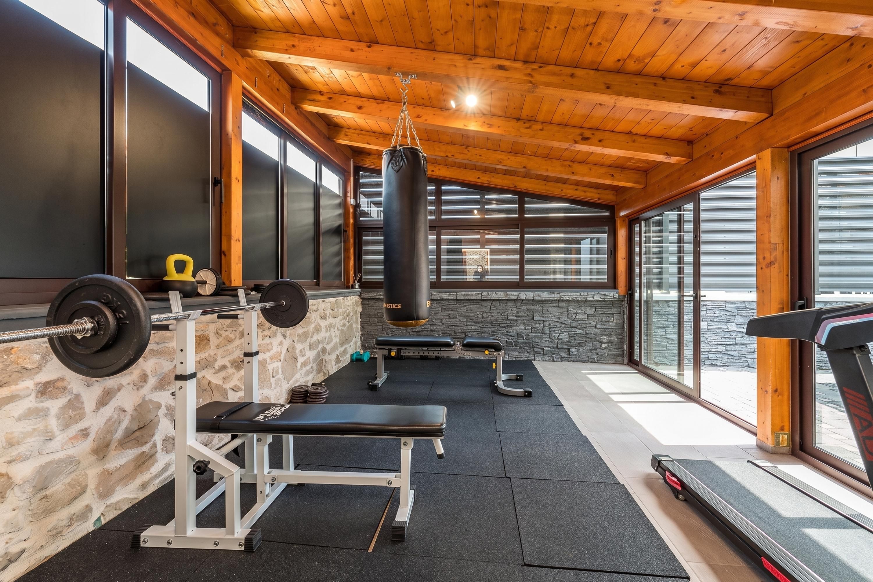 A gym with a stone wall, wooden ceiling, and large windows.