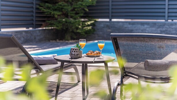A poolside area with lounge chairs, a table with food and drinks, and a view of the pool. - S Villa With Pool, Jacuzzi & Gym (Vodice)