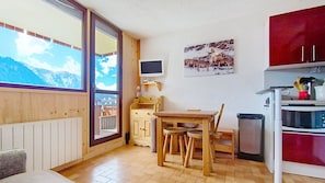 Eine gemütliche Küche mit Holzschränken, einem Esstisch und Bergblick durch das Fenster.