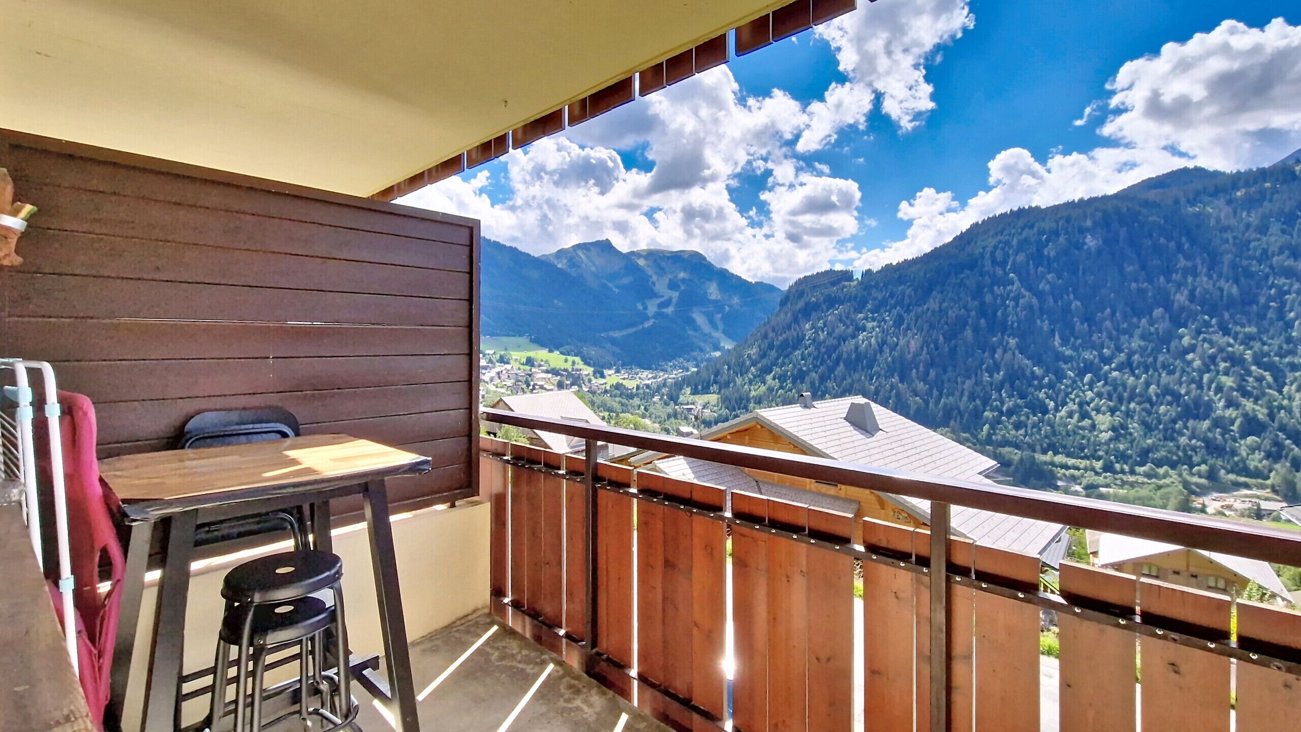 Ein Balkon mit Holzbalkon, einem Tisch und einem Stuhl.