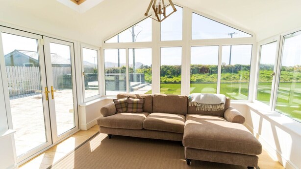 A spacious room with a large sectional sofa, a herringbone-patterned rug, and a skylight. - 5 The Cloisters - Waterville (Waterville)