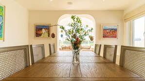 A dining room with a long wooden table, chairs with woven backs, and a vase with a plant. - 5 The Cloisters - Waterville (Waterville)