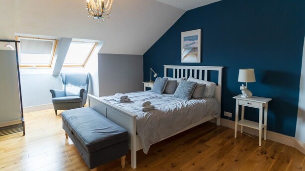 A bedroom with a bed, a chair, a nightstand, a lamp, and a chandelier. - Lig do Scíth - Cahersiveen (Cahersiveen)