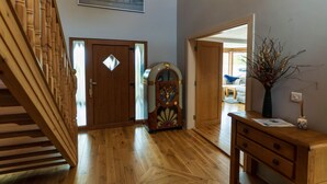 A wooden staircase, a door with a diamond-shaped window, a vintage radio, and a vase with branches on a wooden table. - Lig do Scíth - Cahersiveen (Cahersiveen)