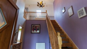 A staircase with wooden railings leading to a second floor, a chandelier, and framed artwork on the walls. - Lig do Scíth - Cahersiveen (Cahersiveen)