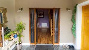 A hallway with a wooden floor, a door with a glass panel, and a staircase leading to an upper level. - Lig do Scíth - Cahersiveen (Cahersiveen)