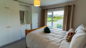 Een hotelkamer met een bed, een raam met gordijnen, een spiegel en een kledingkast.