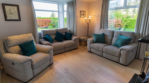 Een woonkamer met twee banken, een stoel en een vloerlamp.
