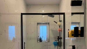 Ein modernes Badezimmer mit einer Duschkabine, einer Toilette und einem Waschbecken mit Spiegel darüber.