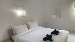 Ein Schlafzimmer mit einem Bett, Nachttischen, einem Fenster und einem Spiegel.