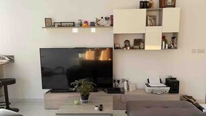 Ein modernes Wohnzimmer mit Flachbildfernseher, Couch, Couchtisch und Einbauschränken mit Dekorationselementen.