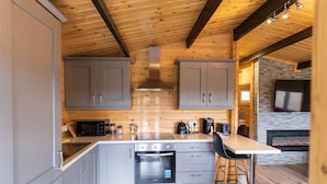 Eine moderne Küche mit grauen Schränken, einem Edelstahlbackofen und einem Kamin aus Naturstein.