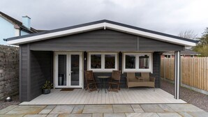 Eine überdachte Terrasse mit Tisch und Stühlen, ein kleiner Gartenbereich und Blick auf den Garten.