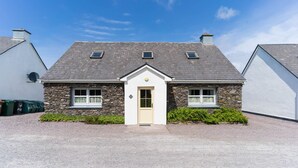 Ein zweistöckiges Steinhaus mit einem mittleren Eingang, zwei Fenstern im Obergeschoss und einer Schotterauffahrt.