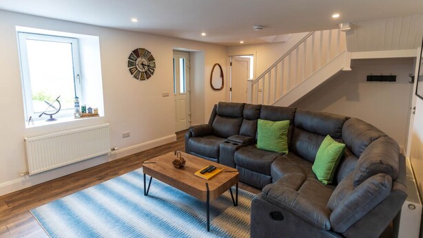 Ein Wohnzimmer mit Sofa, Couchtisch, einer Uhr und einer Treppe.