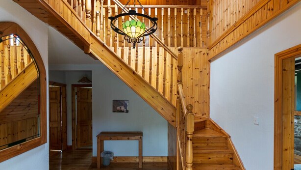 Een houten trap met een glazen lantaarn, een houten bank en een deur die naar een andere kamer leidt.
